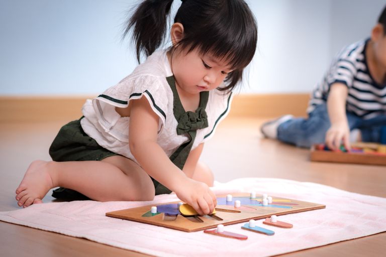 Enfant manipulant de petits objets, travaillant sur de la motricité fine