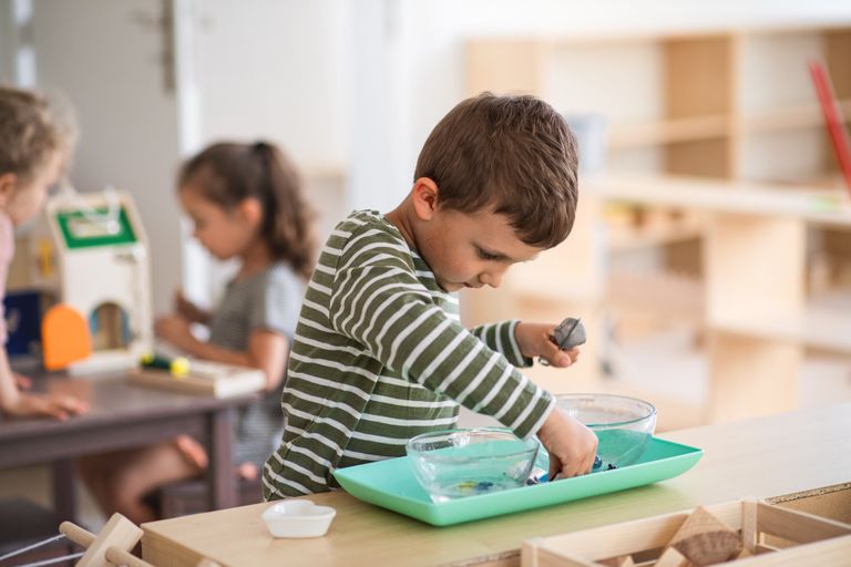 Enfant manipulant de petits objets, travaillant sur de la motricité fine