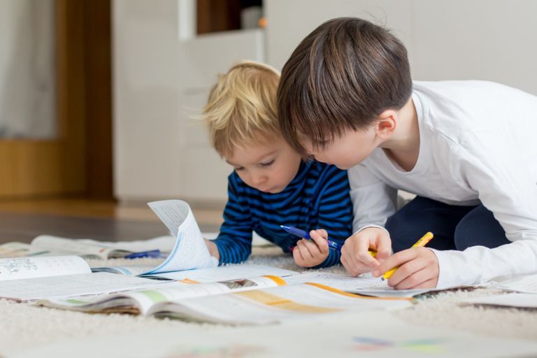 Two boys reading and writing, working together